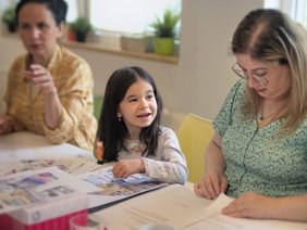 Mädchen mit Frauen am Tisch beim Basteln